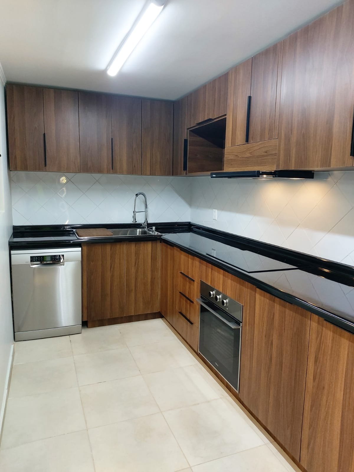 Cocina remodelada con muebles de melamina oscura y cubierta negra, Providencia