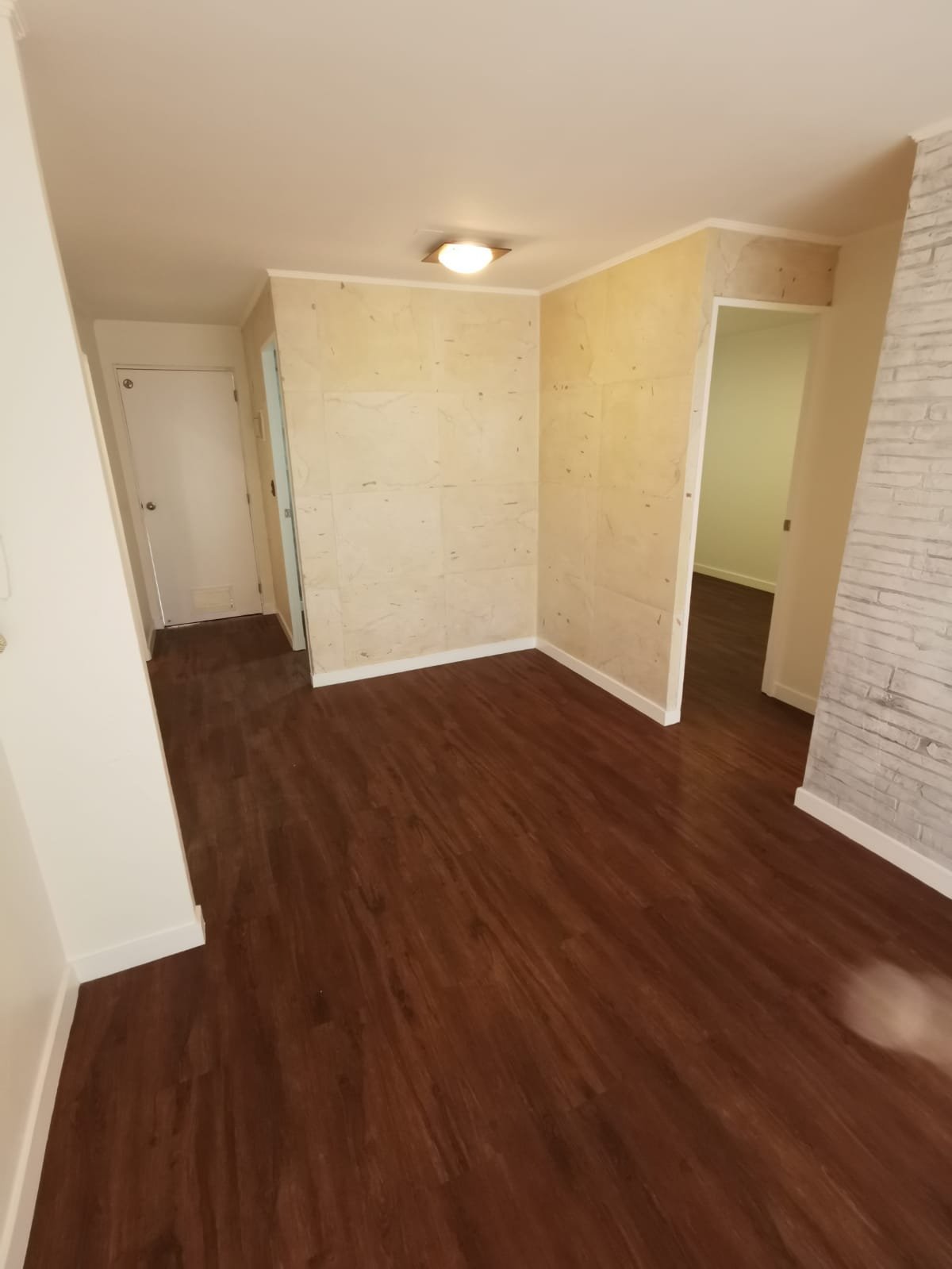 Pasillo remodelado con piso flotante y revestimiento decorativo en departamento de Ñuñoa